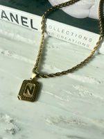 gold square pendant chain necklace on marble with chanel fashion book