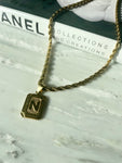 gold square pendant chain necklace on marble with chanel fashion book